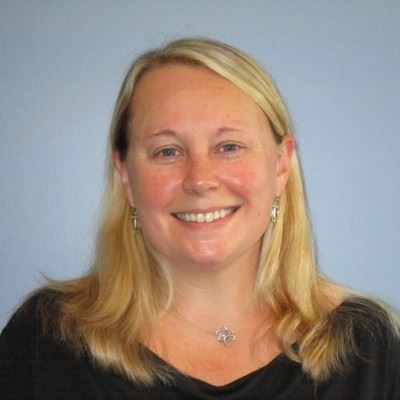 Woman smiling with blonde hair in a navy blue shirt