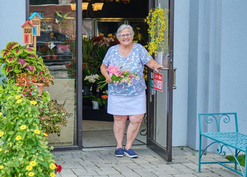 Helen, owner of Concord Flower Shop, at her business door